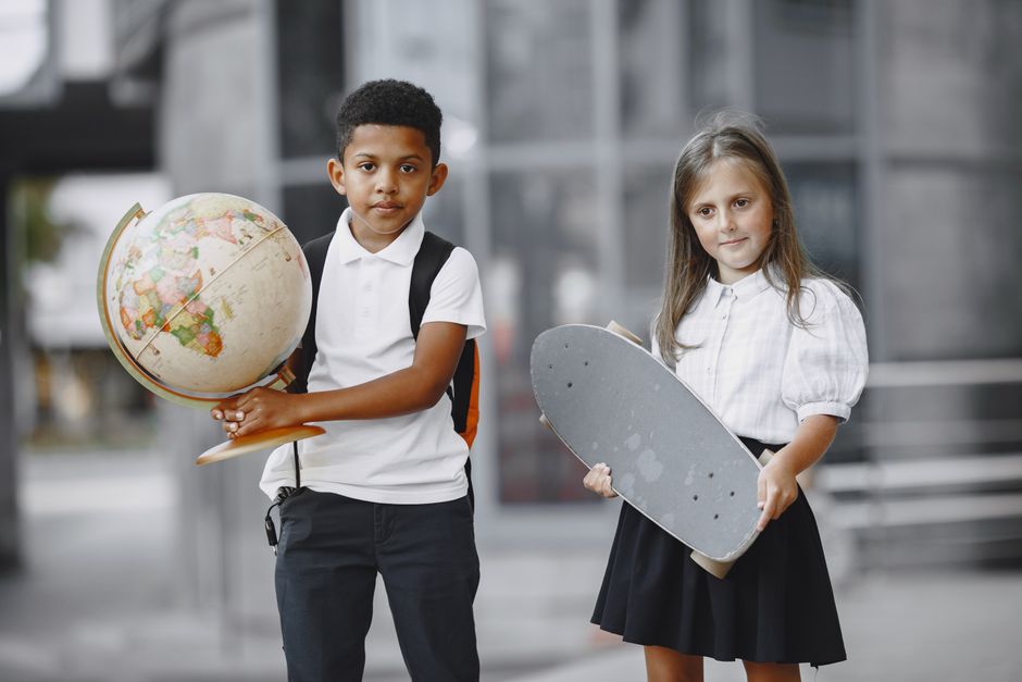 Two students standing outside with a globe and skateboard, embracing diversity and education.